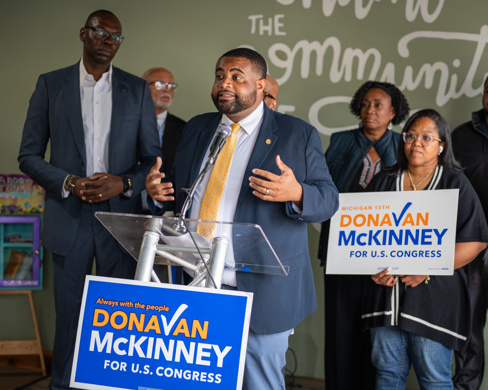Donavan McKinney speaking at a campaign event with supporters standing behind him
